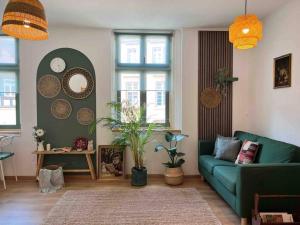 a living room with a green couch and some windows at Cozy apartment in city center “Le petit Paris” in Lahr
