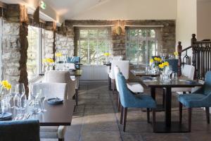 uma sala de jantar com mesas, cadeiras e janelas em Aysgarth Falls Hotel & Restaurant em Aysgarth