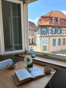 einen Tisch mit einem Buch und eine Blume am Fenster in der Unterkunft Cozy apartment in city center “Le petit Paris” in Lahr