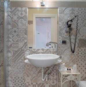 Un baño con un lavabo blanco y un espejo. en Porta Nazionale Dependance, en Noto