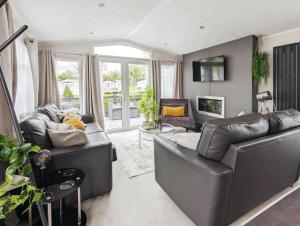 a living room with two leather couches and a tv at Lakewood Lodge in South Cerney