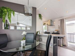 eine Küche und ein Esszimmer mit einem Glastisch und Stühlen in der Unterkunft Lakewood Lodge in South Cerney