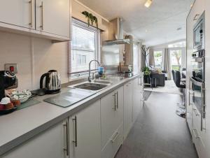 eine Küche mit weißen Schränken und einem Waschbecken in der Unterkunft Lakewood Lodge in South Cerney