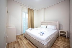 a bedroom with a large white bed with two candles on it at Mamma's Apartments in Sarandë