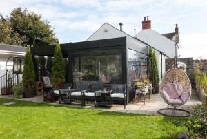 a black extension of a house with chairs and windows at Manse On The Beach in Kirkistown