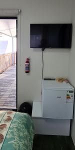 a room with a television on a wall with a bed at Villa Dubaai in Mossel Bay