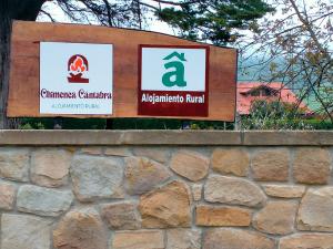 a sign on a stone wall next to a building at La Chimenea Cantabra in Oreña