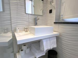 un bagno bianco con lavandino e specchio di By the Beach a Nazaré