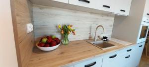 a kitchen counter with a bowl of fruit and flowers at Apartament Garden AiR in Sztutowo