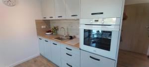 a white kitchen with a stove and a sink at Apartament Garden AiR in Sztutowo