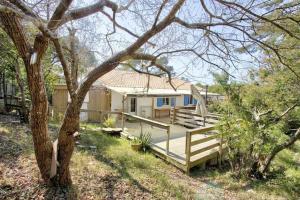 une maison avec une terrasse en bois et un arbre dans l'établissement Villa dans la pinède, au calme à proximité du lac et des plages, jusqu'à 7 personnes, à Biscarrosse