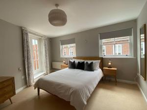 a bedroom with a large bed and two windows at The Penthouse, Winchester in Winchester