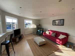 a living room with a red couch and a tv at The Penthouse, Winchester in Winchester