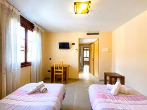 2 camas en una habitación con mesa y ventana en Hostal Ainoa, en Berlanga de Duero