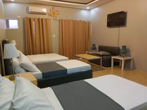 a hotel room with two beds and a tv at Yas Villa - Stay, Play & Enjoy. Bagac, Bataan in Bagac