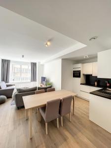 Cosy Apartment Brussels - Avenue Louise في بروكسل: مطبخ وغرفة معيشة مع طاولة وكراسي