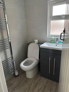 een badkamer met een toilet, een wastafel en een raam bij Cottage, 10 mins Train / River in Burnham on Crouch