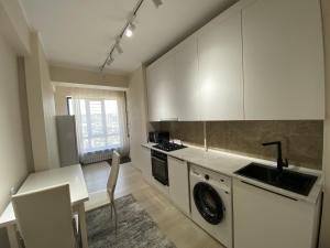 a kitchen with white cabinets and a table and a sink at A cosy apartment in Osh