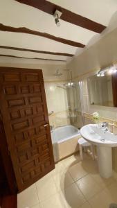 a bathroom with a door and a sink and a tub at La Posada de Chinchilla in Chinchilla de Monte Aragón