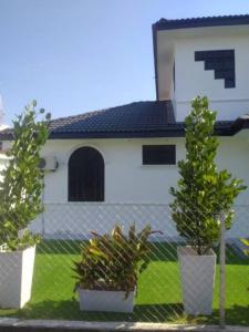 a white house with two potted trees in front of it at Villa President Homestay -4 bedroom Aircond WIFI Vacations Home in Kampung Kerangi