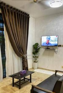a living room with a couch and a tv and a curtain at Villa President Homestay -4 bedroom Aircond WIFI Vacations Home in Kampung Kerangi