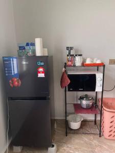 a kitchen with a black refrigerator and a microwave at Villa President Homestay -4 bedroom Aircond WIFI Vacations Home in Kampung Kerangi