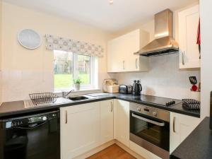 a kitchen with white cabinets and black counter tops at 12 The Dell in Norwich