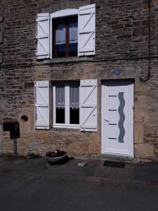 ceglany budynek z białymi drzwiami i oknami w obiekcie GITE ANNA w mieście Le Châtelet-sur-Sormonne