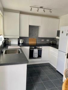 a kitchen with white cabinets and a sink at Manchester 2 Bedroom House with Garden in Manchester