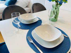 - une table blanche avec deux assiettes et des verres dans l'établissement KYANIT APARTMENT: FREE PARKING + POOL + NETFLIX, à Wuppertal