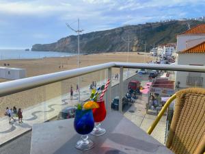 a balcony with two cocktails on a table with a view of the beach at Hotel Oceano in Nazaré