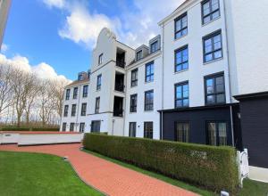 a large white building with a red brick driveway at Triton suite Duinhof - Stijn Albrechtsstraat 1-6 in Cadzand