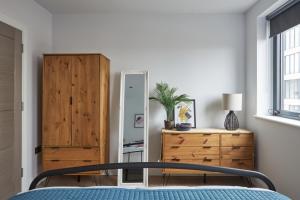 1 dormitorio con 1 cama y armario de madera en Kings Oak House by Viridian Apartments, en Londres