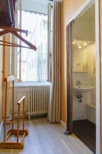 a bathroom with a sink and a window and a chair at Hotel du Théatre in Lyon +37 photos