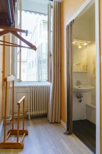 baño con lavabo, ventana y silla en Hotel du Théatre, en Lyon