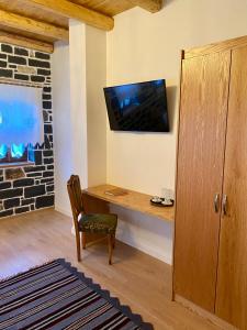 Habitación con escritorio y TV en la pared. en Hotel Kaso Ervehe, en Përmet