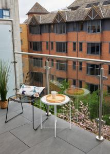 a table and chair on a balcony with a building at Kings Oak House by Viridian Apartments in London
