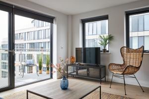 uma sala de estar com uma televisão e uma cadeira em Kings Oak House by Viridian Apartments em Londres