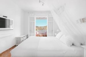 Un dormitorio blanco con una gran cama blanca y una ventana en Mykonian Atmosphere en Kalo Livadi