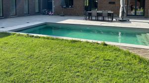 uma piscina num quintal com relva verde em Guest House and swimming pool em Romsée