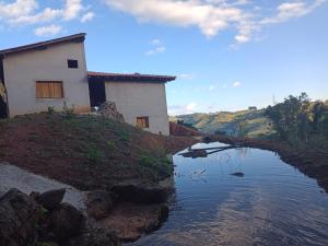 a house on a hill next to a body of water at Chacara Usina D Agua - Socorro-SP in Socorro