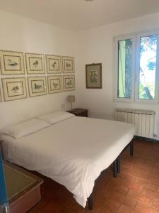 Cama blanca en habitación con ventana en La Casa Del Pescatore B&B, en Portovenere