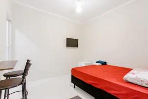 1 dormitorio con cama, mesa y TV en Pousada Casa da Fernanda, Suíte Moon en Praia Grande
