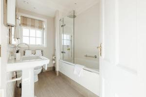 a white bathroom with a sink and a tub at Victoria in Holkham
