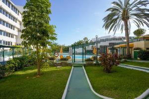 uma passarela num parque com piscina e palmeiras em Stylish apartment with stunning sea view. em Maspalomas