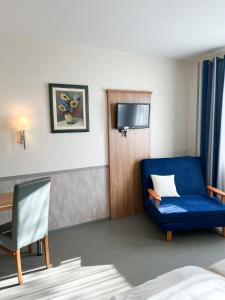 una camera d'albergo con divano blu e TV di Hotel Garni Illertal ad Altenstadt