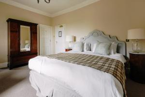 a bedroom with a large white bed and a mirror at Victoria in Holkham