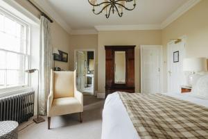 a bedroom with a bed and a chair and a chandelier at Victoria in Holkham