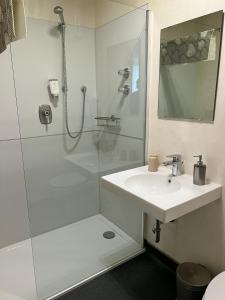 een witte badkamer met een douche en een wastafel bij Hotel Garni Illertal in Altenstadt