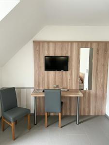 einen Schreibtisch mit 2 Stühlen und einen TV an der Wand in der Unterkunft Hotel Garni Illertal in Altenstadt